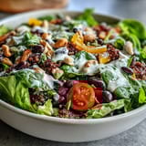 Vibrant Rainbow Salad Bowl with quinoa, beans, and crunchy nuts, dressed in zesty lemon vinaigrette.