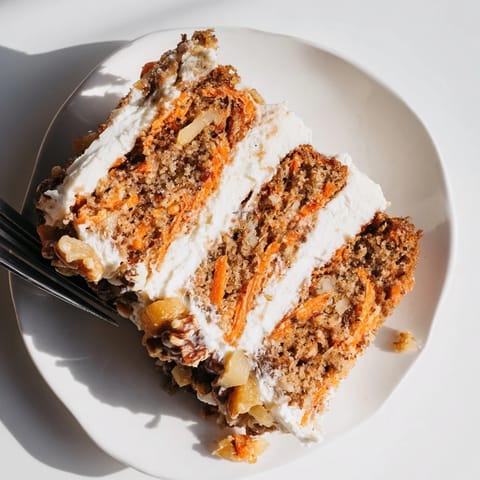 Whole Carrot Cake with cream cheese frosting and chopped walnuts, ready to serve at a spring gathering.