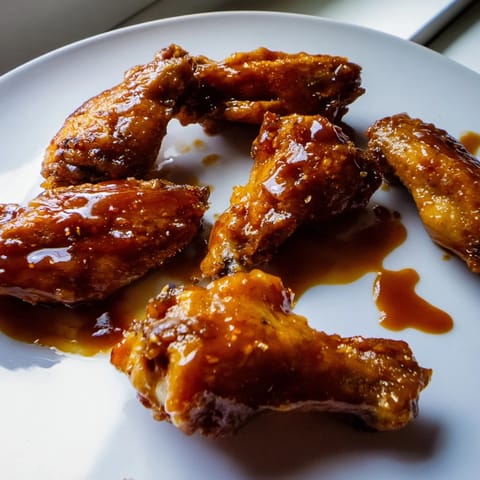 Crispy Honey BBQ Chicken Wings tossed in glossy, smoky sauce, piled high on a platter ready for game day snacking.