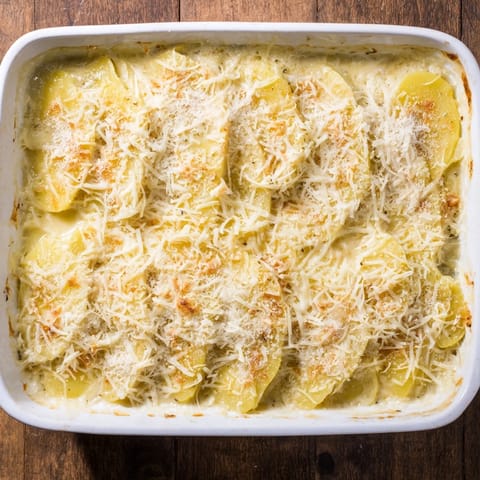 Creamy sliced Yukon Gold potatoes layered with Gruyère and Parmesan in a baking dish.