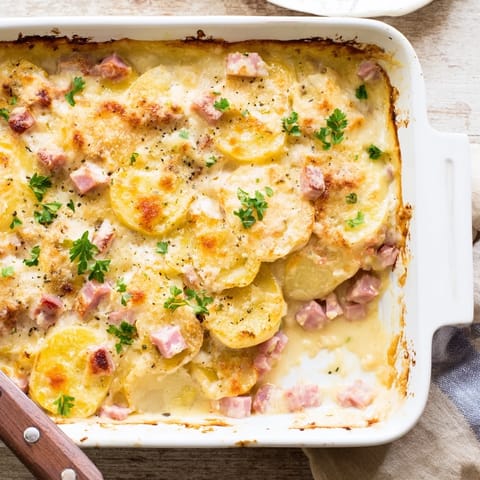 A close-up of creamy Scalloped Potatoes with Ham showing tender potato layers, diced ham, and a rich, cheesy sauce.
