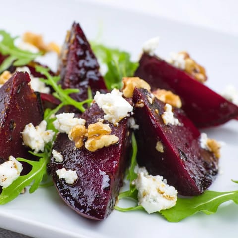 Roasted beet goat cheese salad topped with crumbled cheese and toasted walnuts on arugula.  
