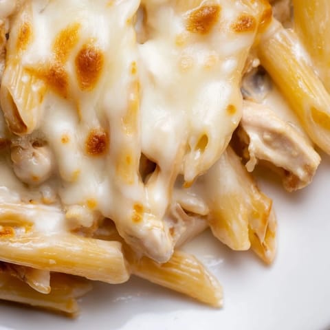 Golden-brown Chicken Ranch Pasta Bake with melted mozzarella and a creamy ranch sauce, served in a white casserole dish.