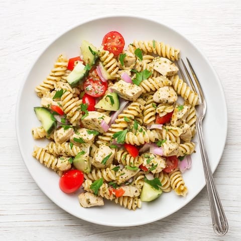 Bright, colorful bowl of Honey Mustard Chicken Pasta Salad with crisp cucumber and cherry tomatoes.