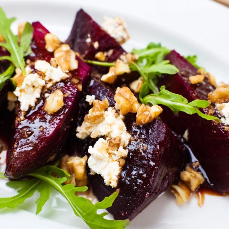 Colorful Roasted Beet Goat Cheese Salad drizzled with vinaigrette, garnished with fresh chives for serving.