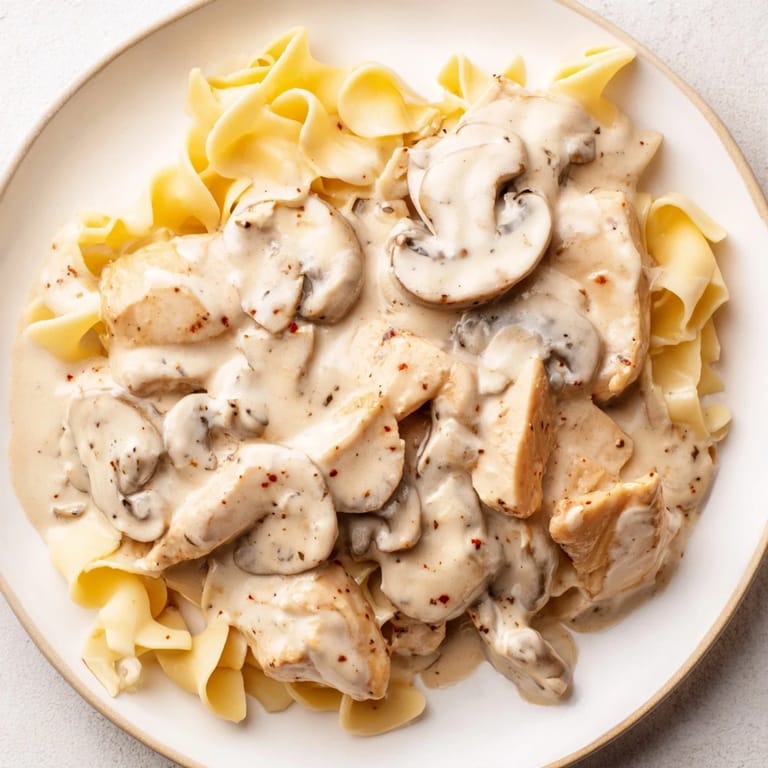A comforting bowl of Chicken and Mushroom Stroganoff features golden sautéed chicken, earthy mushrooms, and silky sour cream sauce on egg noodles.