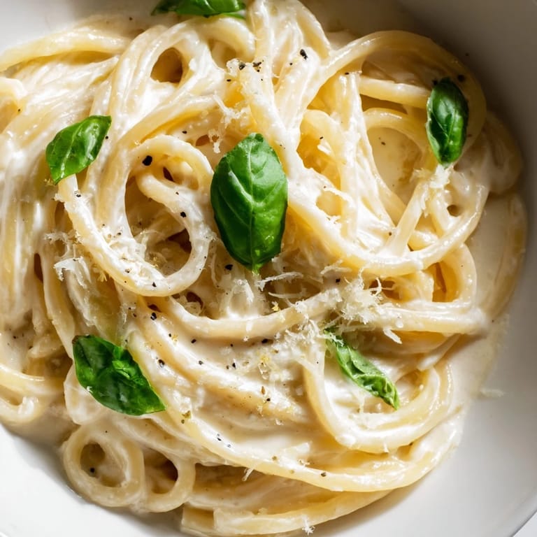 Vivid serving suggestion for Lemon Ricotta Pasta, featuring a wedge of lemon and extra Parmesan beside a glass of white wine.